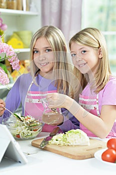 Two girls in pink aprons preparing salad