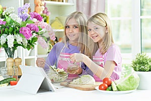 Two girls in pink aprons preparing salad