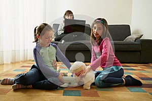 Two girls play in the living room while their mother teleworks