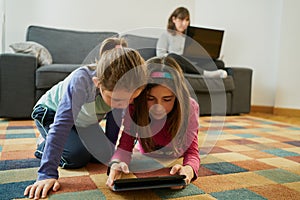 Two girls play in the living room while their mother teleworks