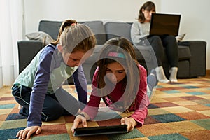 Two girls play in the living room while their mother teleworks