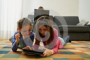 Two girls play in the living room while their mother teleworks