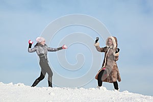 Two girls play snowballs and laugh