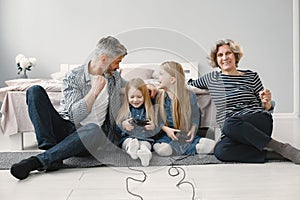 Two girls play video games with grandparents