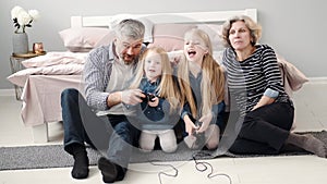 Two girls play video games with grandparents