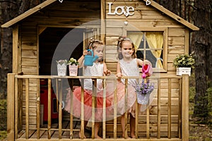 Two girls play with watering can in a tree house