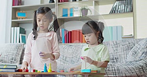 Two girls playing with colorful wooden education toy at home