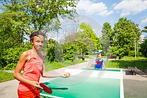 Two girls playing ping pong outside during summer