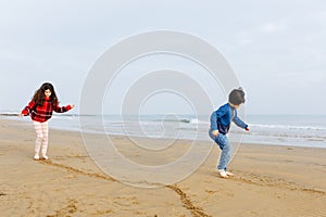 Two girls playing at the sand beach drawing on the sand