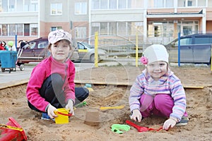 Two girls plays in sandbox on children playground