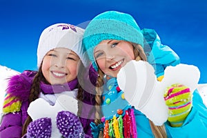 Two girls portrait holding snow hearts