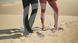 Two girls pose standing barefoot on the sand
