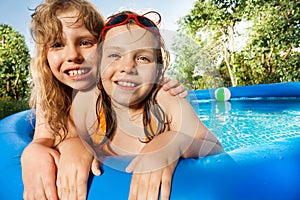 Two girls posing in the swimming pool at sunny day
