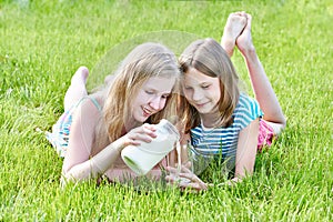 Two girls pours milk in sunny meadow