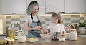 Two girls preparing cookies together in kitchen, kids stir flour