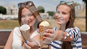 Two girls are presenting ice cream to the viewer.