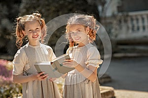 Two girls of primary school schoolgirls read a book in the courtyard of the academy