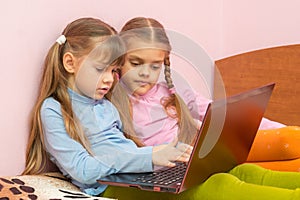 Two girls pushing search query on a laptop keyboard