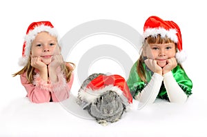 Two girls with a rabbit in red caps of Santy