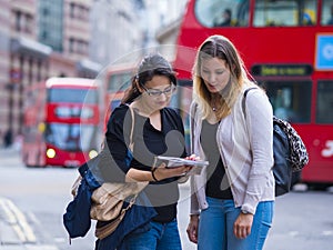 Two girls read a map in the city center of London