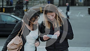 Two girls read a map in the streets of London