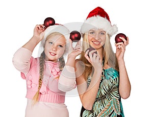 Two girls in red christmas hats hold red fir-tree spheres in han