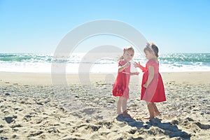 Two girls in red dress on the beach