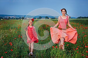 Two girls in red dress walking on poppy field