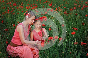 Two girls in red dress walking on poppy field