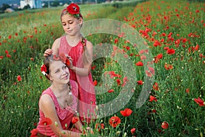 Two girls in red dress walking on poppy field