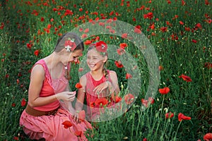 Two girls in red dress walking on poppy field