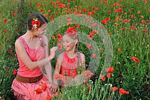 Two girls in a red dress walking on the poppy field in Spring