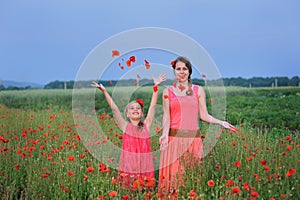 Two girls in a red dress walking on the poppy field in Spring