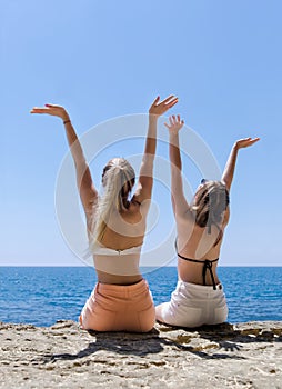 Two girls resting at the sea, rear view