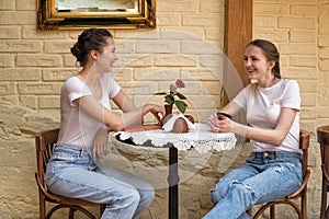 Two girls at round table talking and laughing. Meeting friends, gossip