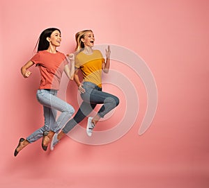 Two girls run fast. Concept of energy and vitality. Pink background photo