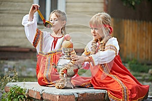 Two girls in Russian national costumes with samovar