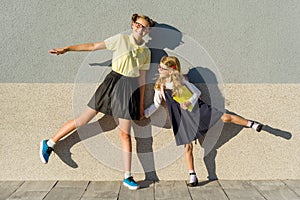 Two girls schoolgirl elementary and high school, posing in front of the camera, on the way to school.