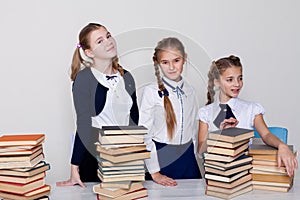 Two girls schoolgirls sit with books at his desk on the lesson at school