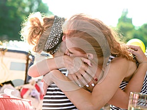 Two girls sea striped shirts hug outside