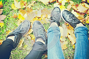 Two girls shoes on autumn leaves, top view, toned photo