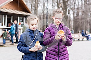 Two girls sisters bought pies in a food truck in a city park and are going to eat