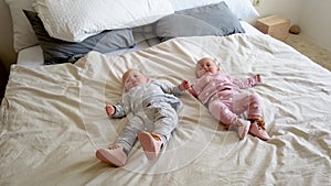 Two girls sisters lie on the bed. Two baby twins on the bed