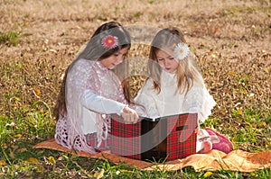 Two girls sisters read the book on the grass