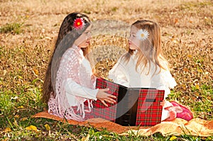 Two girls sisters read the book on the grass