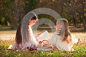 Two girls sisters read the book on the grass