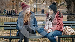 Two girls sit on a bench on Central Park enjoying their time in New York