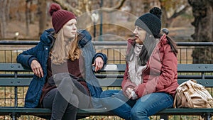 Two girls sit on a bench on Central Park enjoying their time in New York