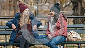 Two girls sit on a bench on Central Park enjoying their time in New York