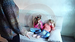 Two girls sit on couch and listen to mom`s remarks about bad behavior.